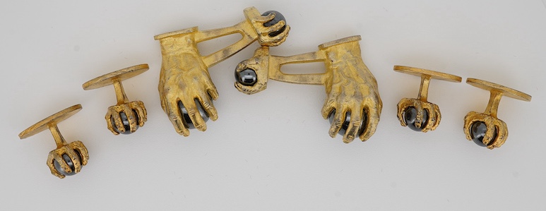 A modern gilt sterling and hematite set six piece dress stud set, modelled as a hand grasping a sphere, comprising a pair of cuff links 30mm and four studs. Condition - poor to fair